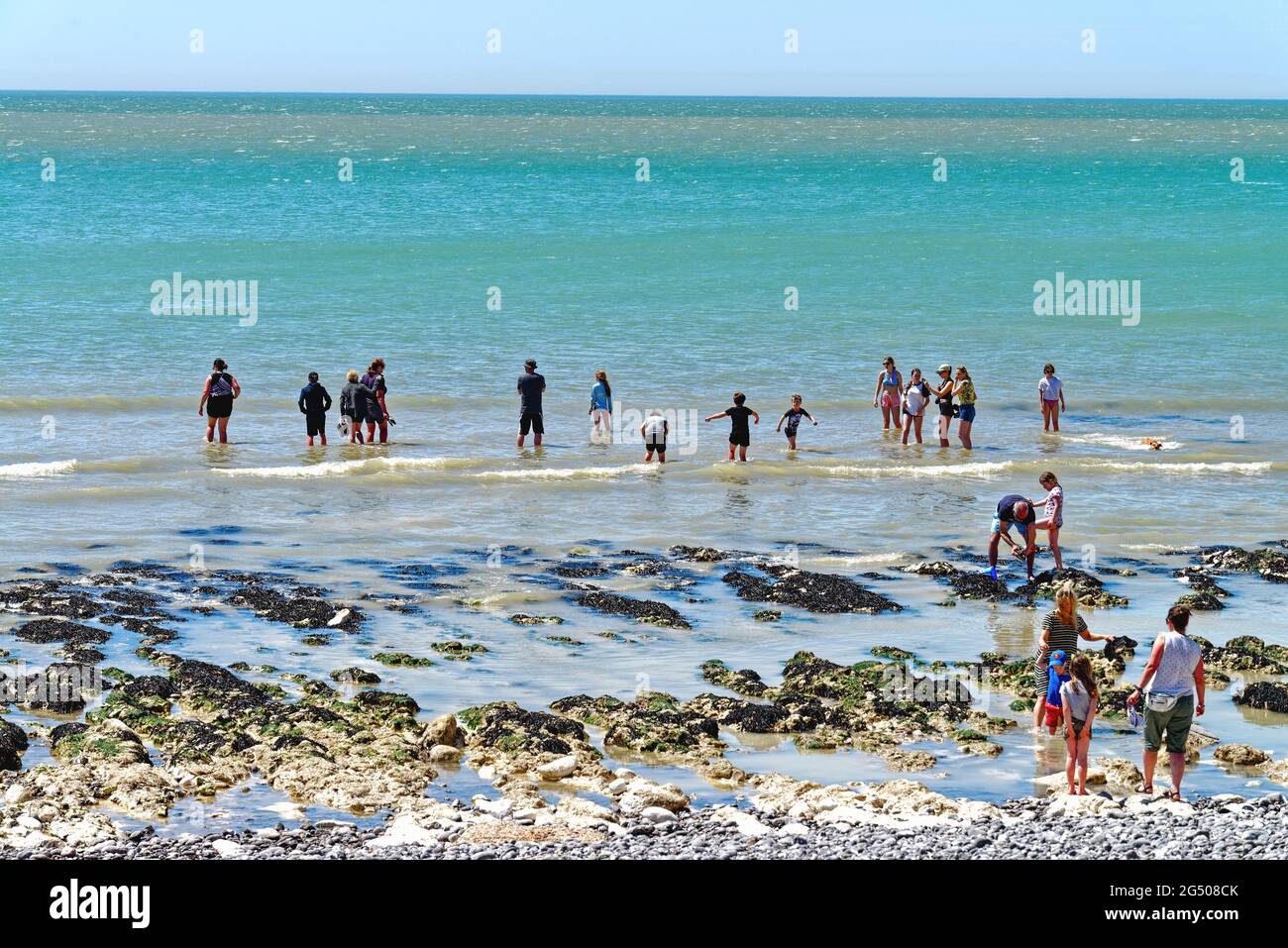 People paddling by the sea edge at Birling Gap beach on a hot sunny summers day near Eastbourne East Sussex England UK Stock Photo