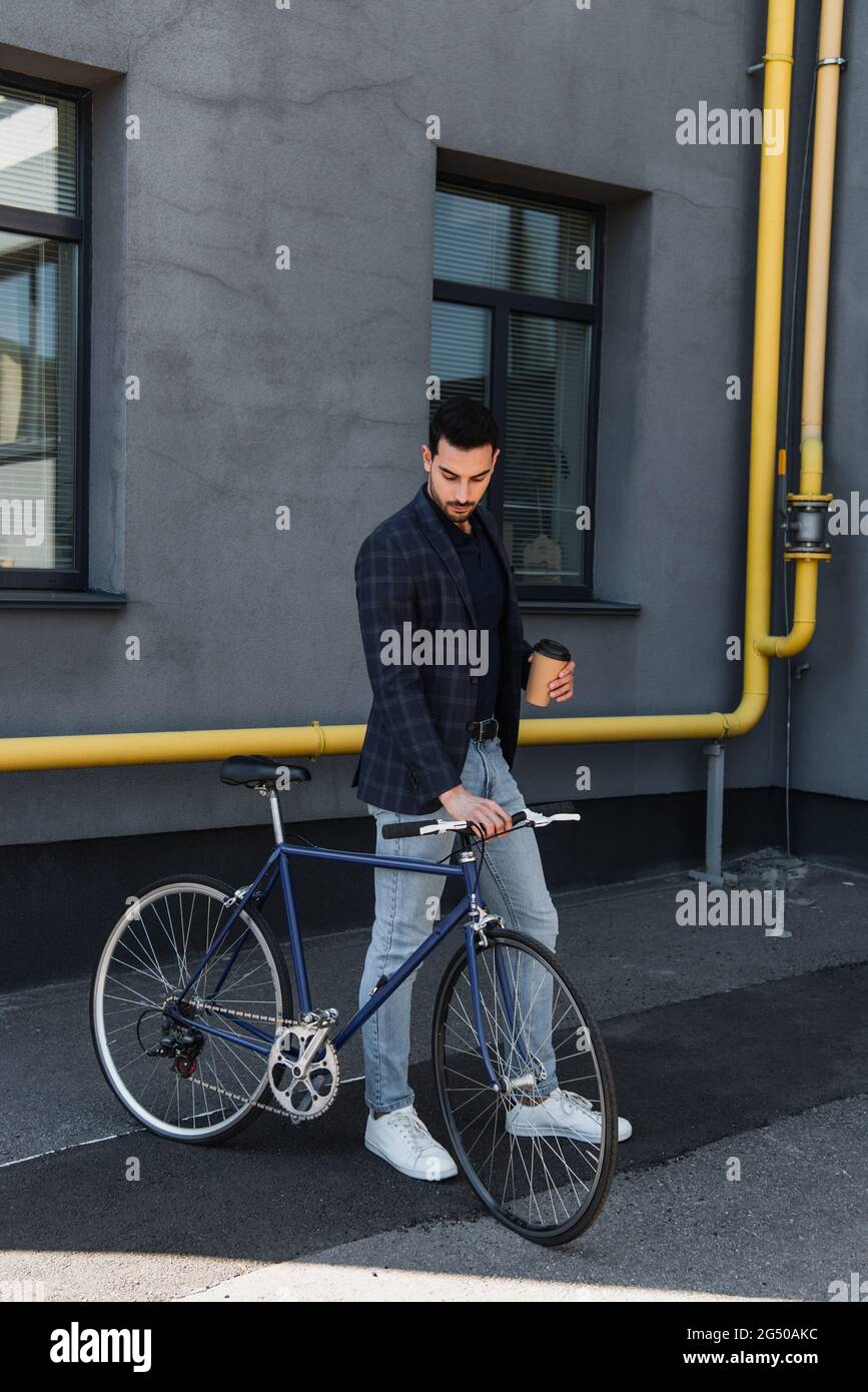 Arabian businessman holding bike and coffee to go outdoors Stock Photo