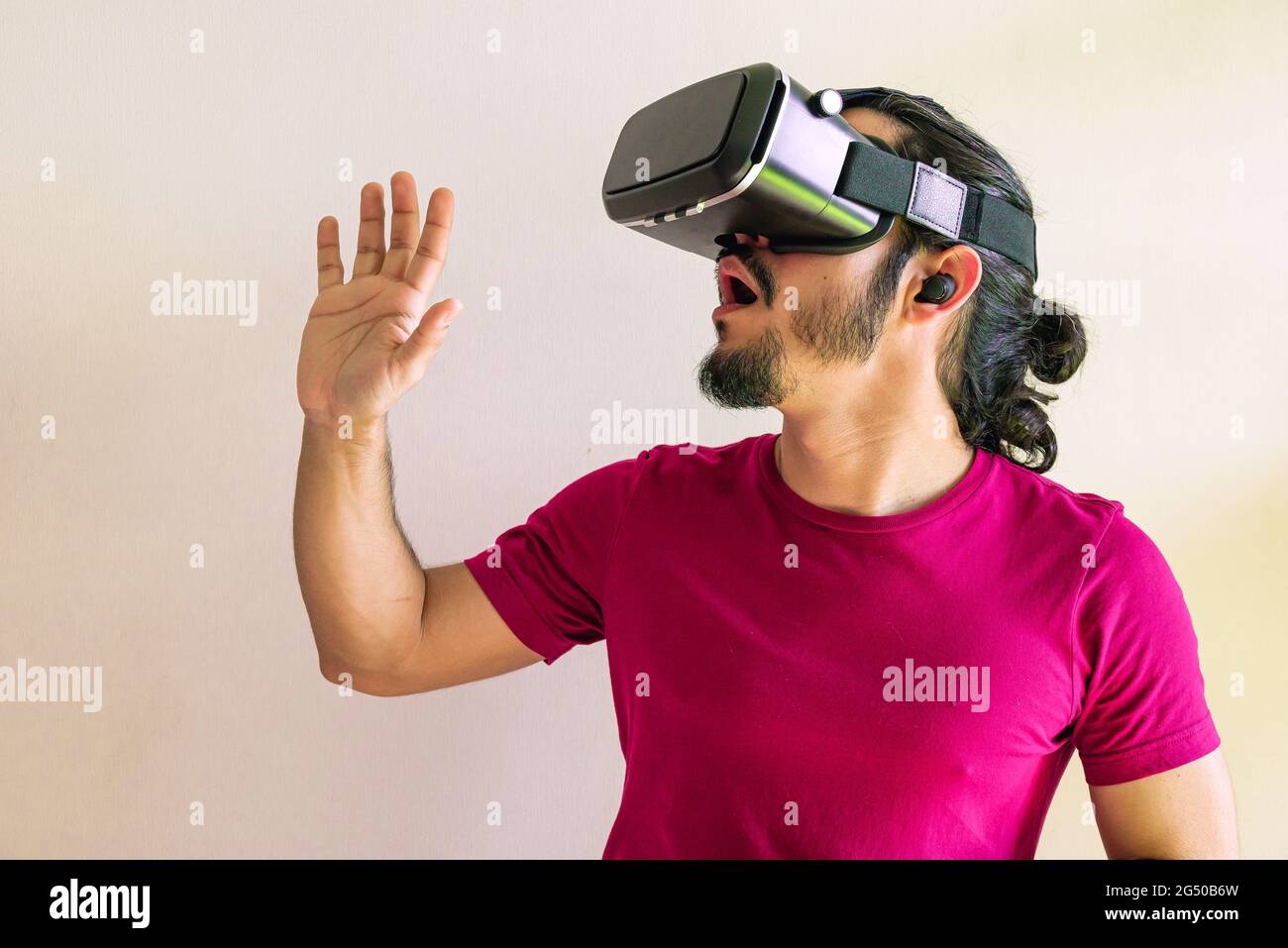 Young latin man using a Virtual Reality Device Glasses at home Stock Photo