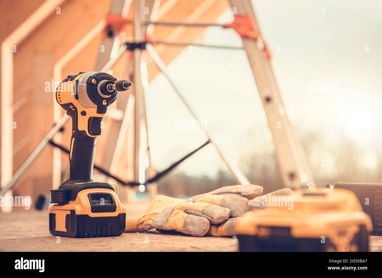 Wooden House Construction Site Power Tools and Safety Gloves Close Up. Construction Industry Theme. Stock Photo