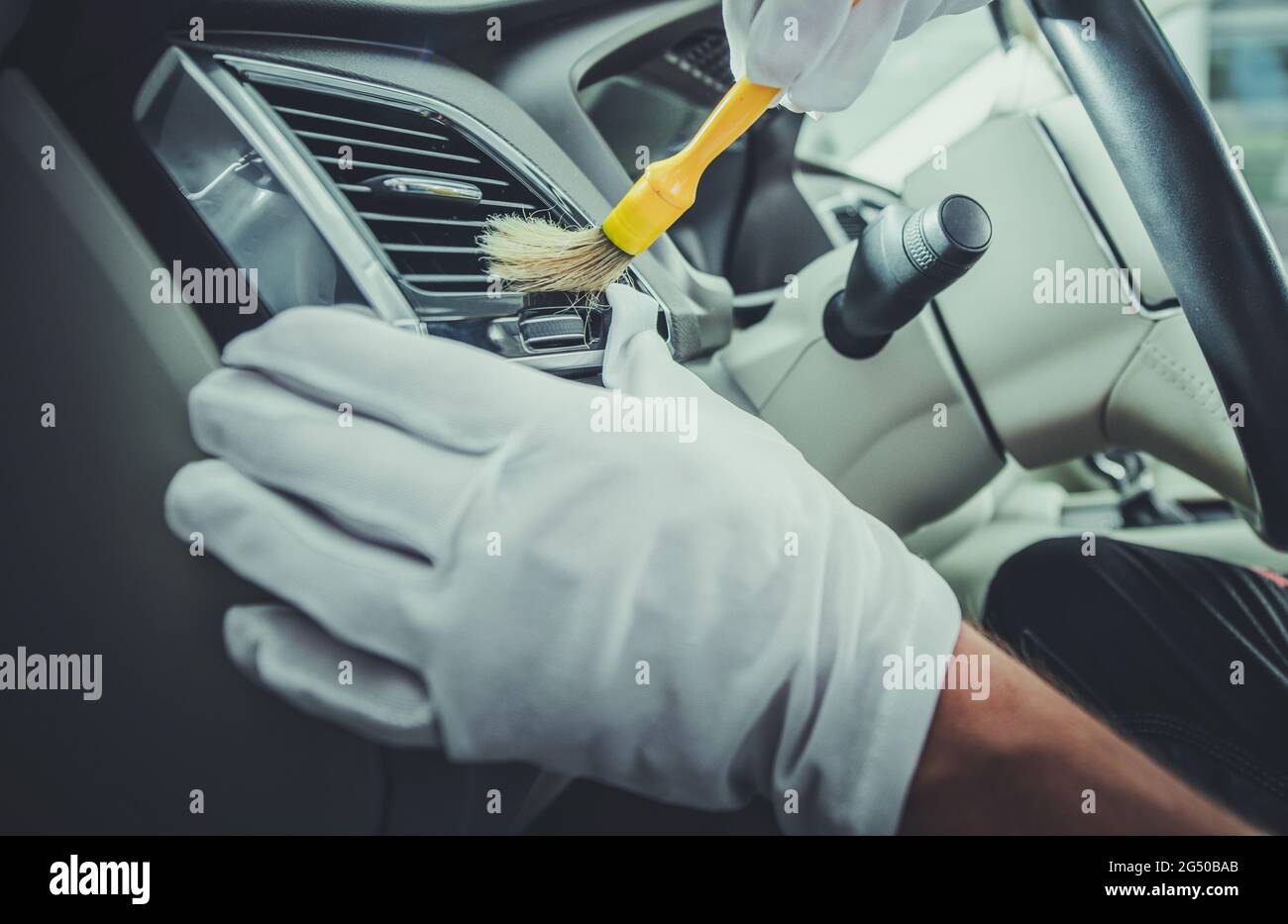 Caucasian Car Detailing Worker Cleaning Luxury Car Interior Using Brush. Automotive Theme. Stock Photo