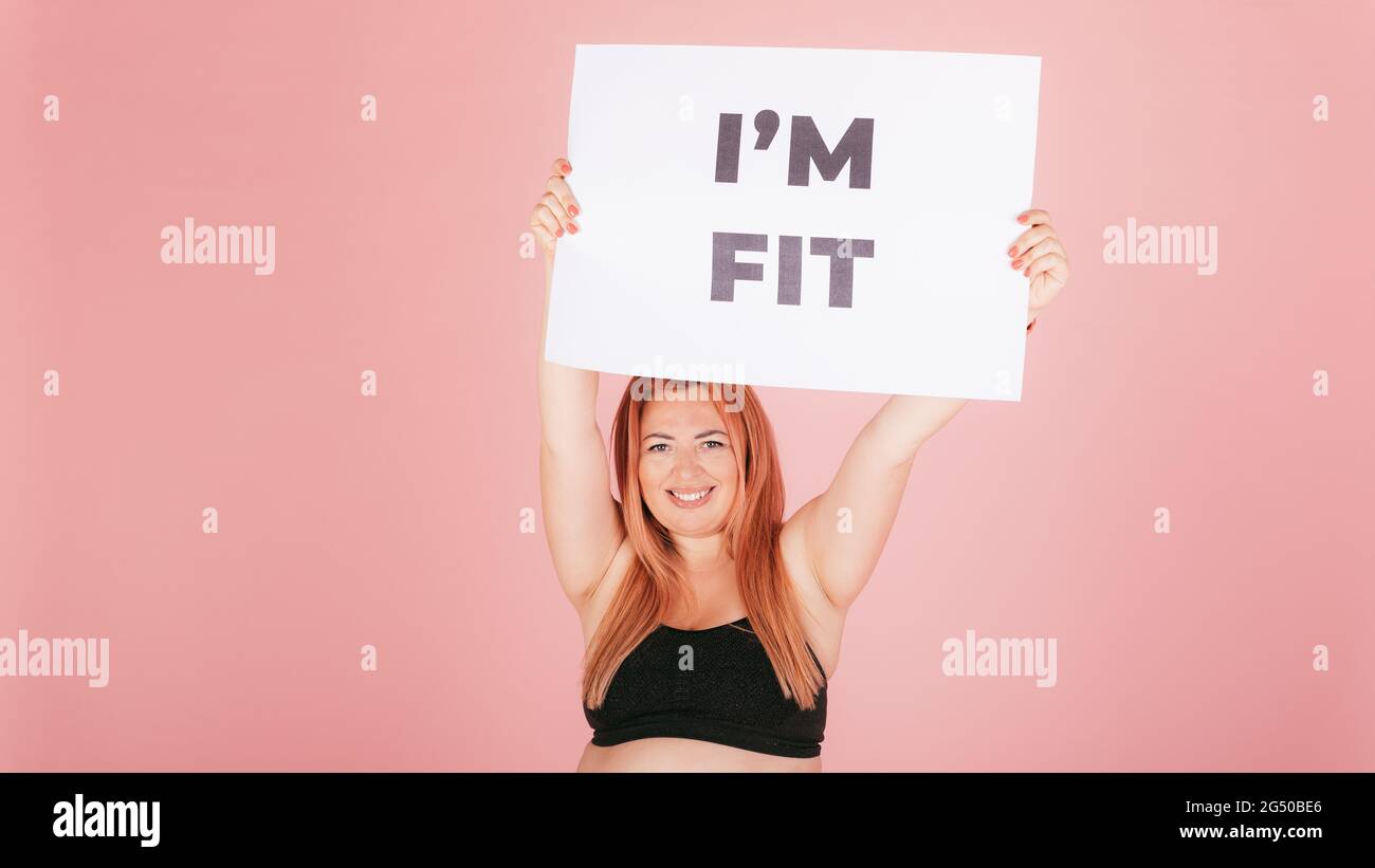 Happy confident woman with plus size body holding an i'm fit placard ...