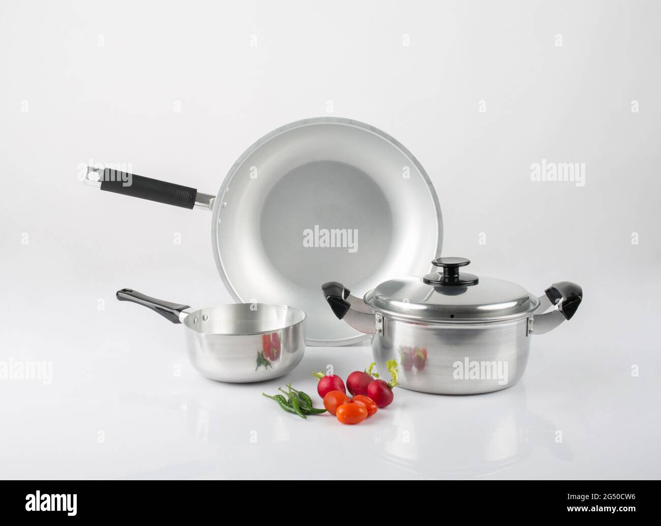Stainless steel pots and pan with vegetables isolated on white background Stock Photo