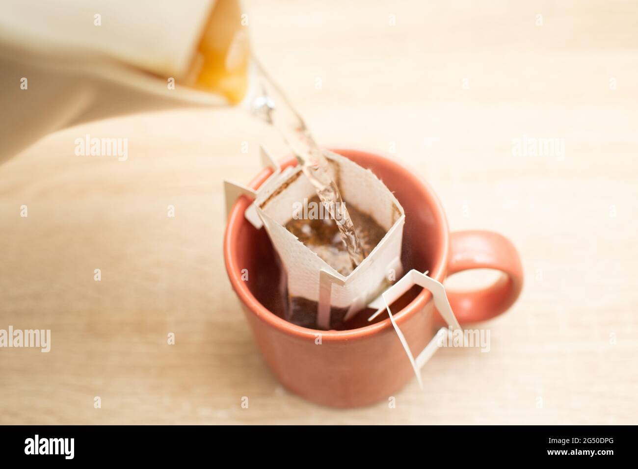 Coffee Drips in cup. Alternative brewing specialty coffee in paper filter bags pouring hot water. Stock Photo