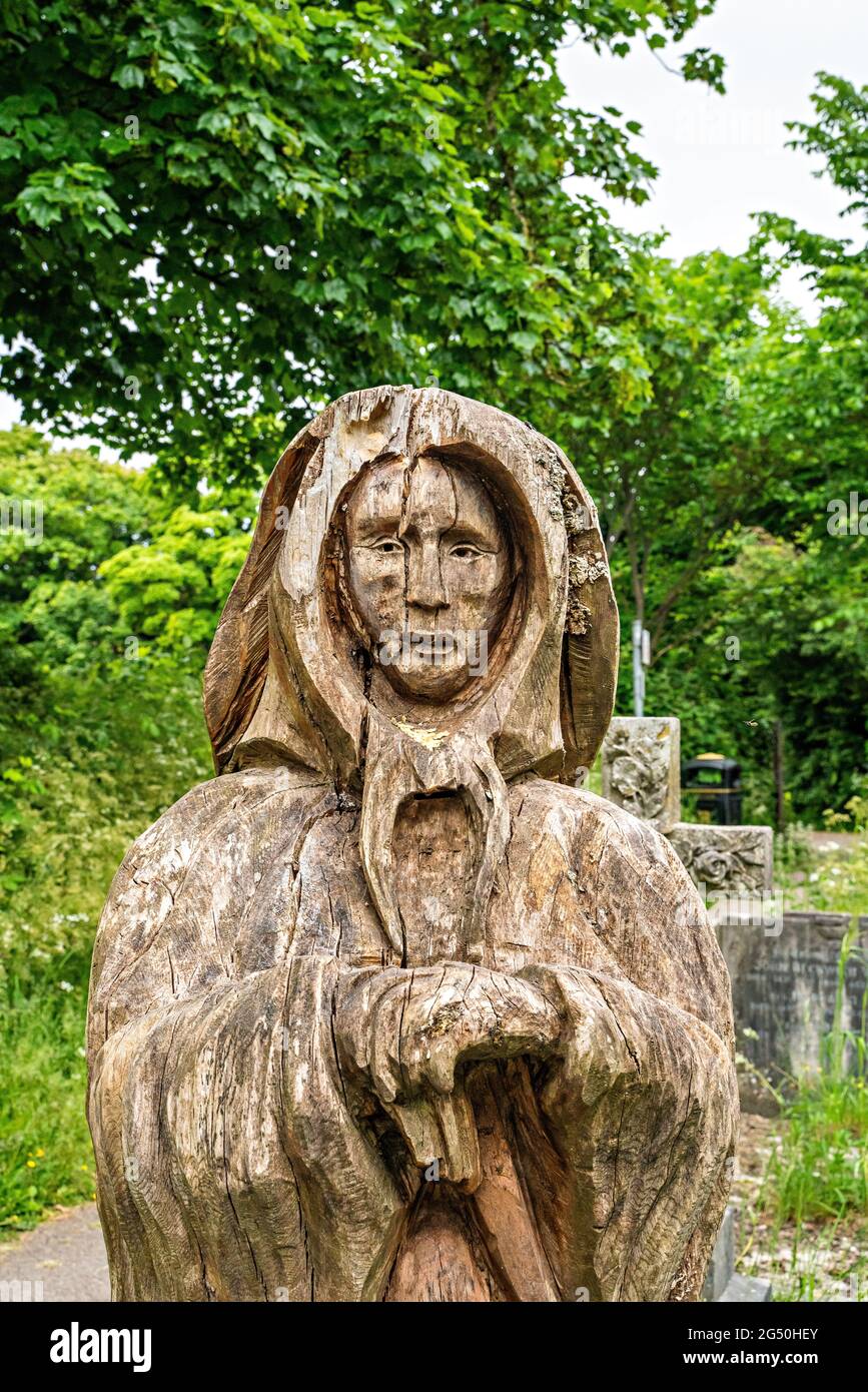 Chainsaw carving of Fisherman's wife (standing opposite her husband)  by Tim Burgess at Holy Trinity churchyard, Morecambe, Lancashire Stock Photo