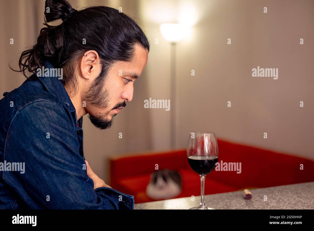 Young latin man depressed drinking red wine at home in the living room Stock Photo