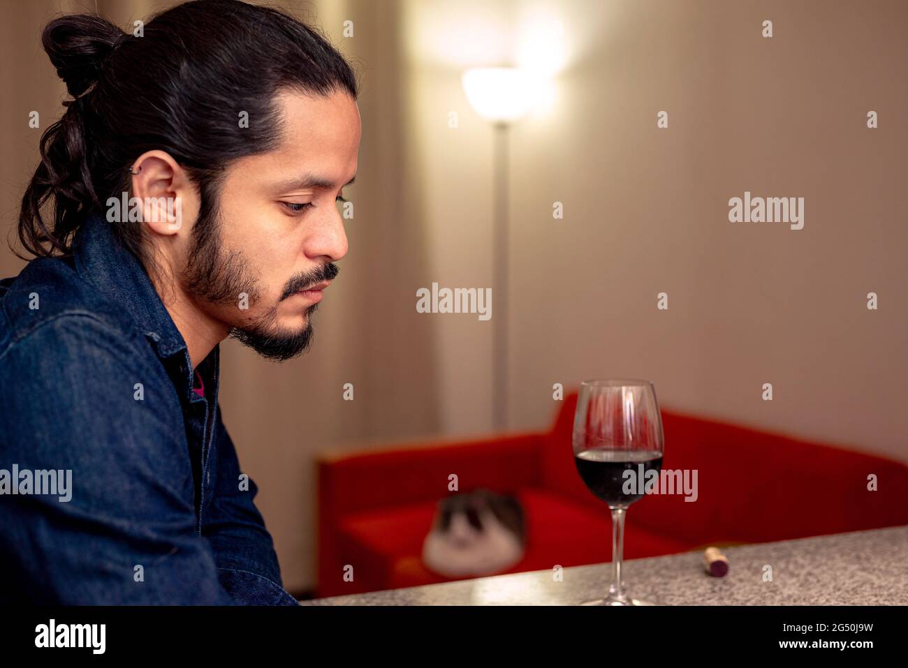 Young latin man depressed drinking red wine at home in the living room Stock Photo