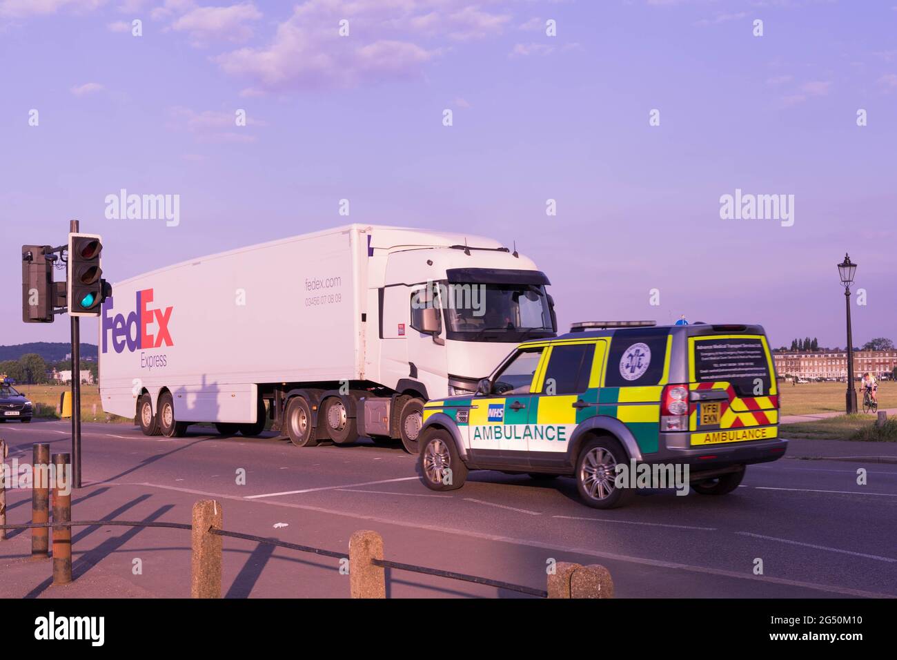 FedEx delivery lorry met London Ambulance at Traffic lights on sunny day, summer, England, UK, Europe Stock Photo