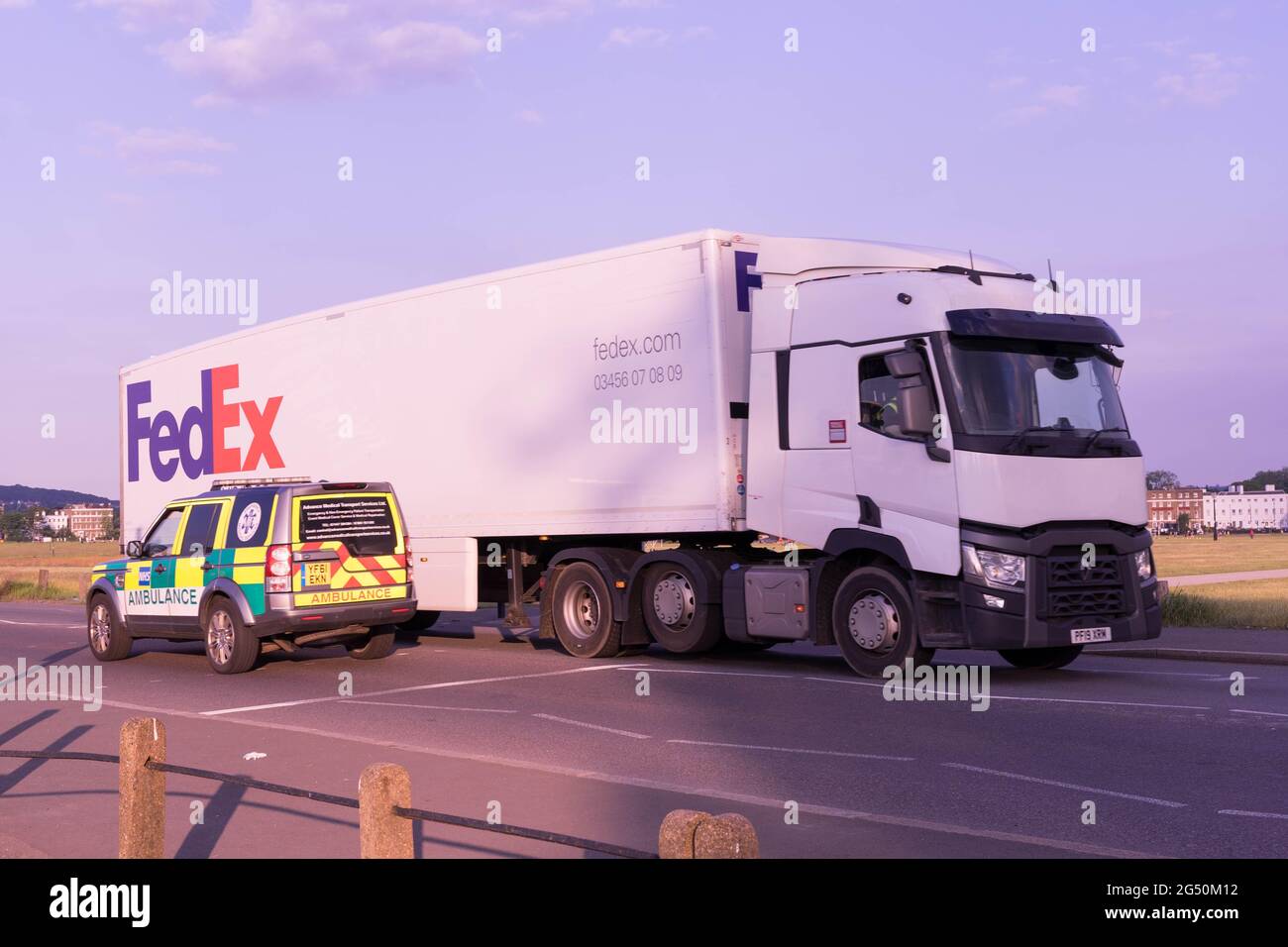 FedEx delivery lorry met London Ambulance at Traffic lights on sunny day, summer, England, UK, Europe Stock Photo