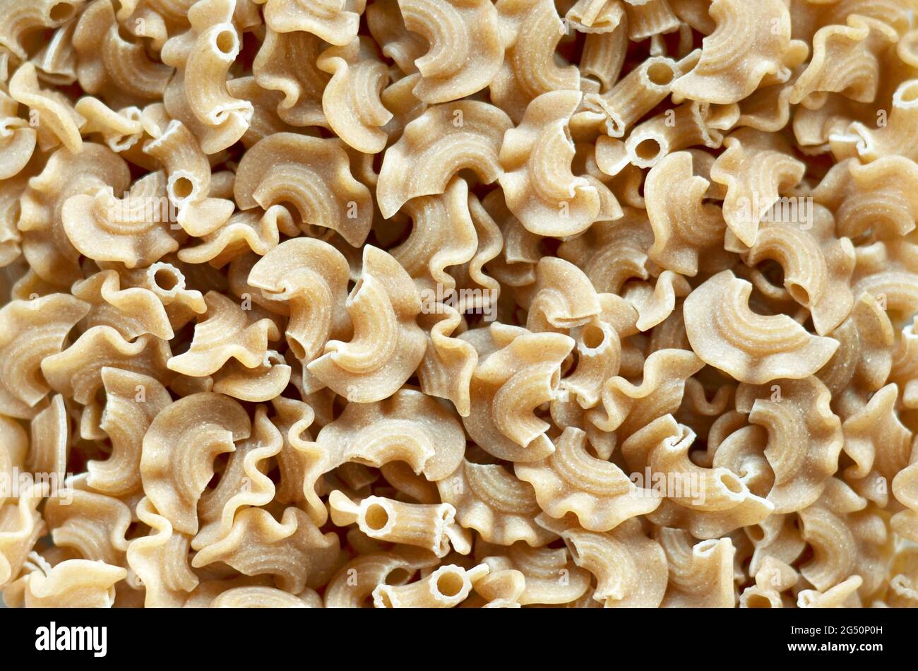 Dry whole wheat macaroni pasta on a full frame, top view. Stock Photo