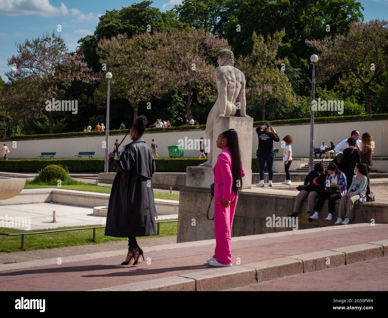 Paris, France, May 2021. Two black beautiful women taking photos, a photo session, a woman in a pink costume. Trocadero square sculpture in the backgr Stock Photo