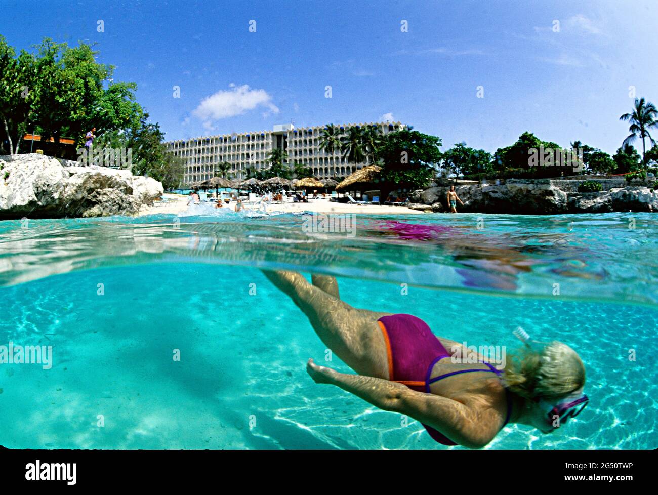 Over-under photo of woman snorkeling off beach,  Curacao, ABC Islands Stock Photo