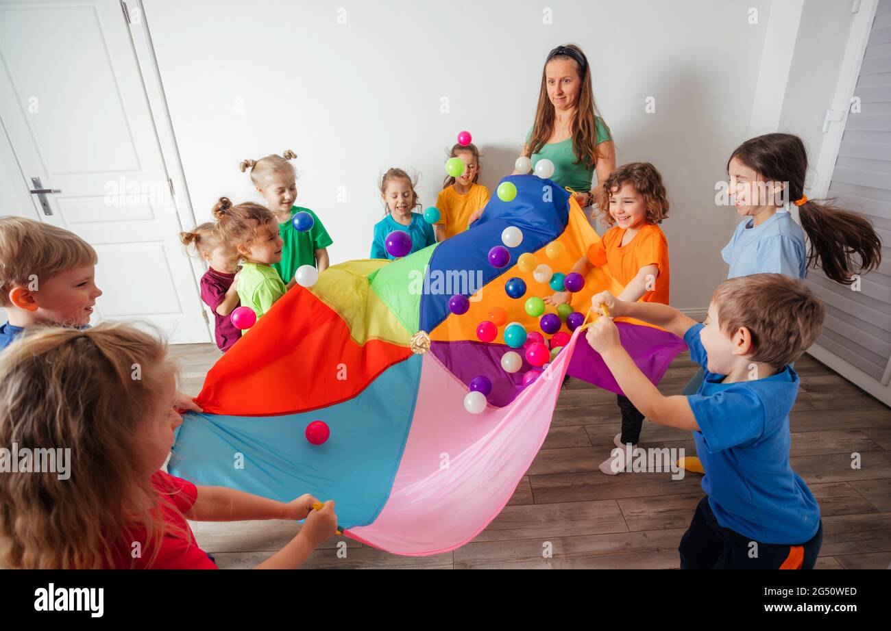 Schoolchildren playing using parachute with friends in gym Stock Photo