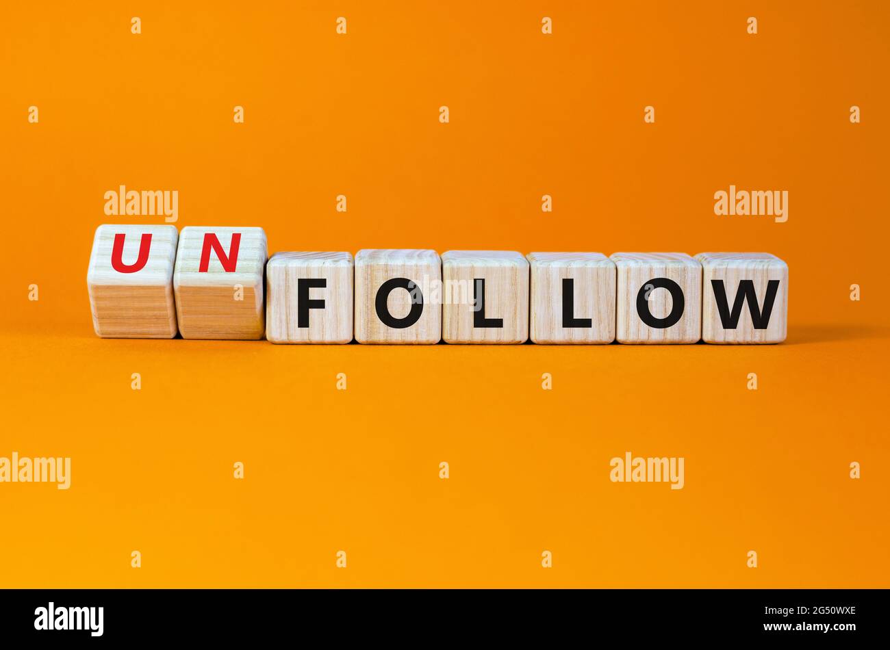 Follow or unfollow symbol. Turned wooden cubes and changed words follow to unfollow. Beautiful orange background, copy space. Business and follow or u Stock Photo