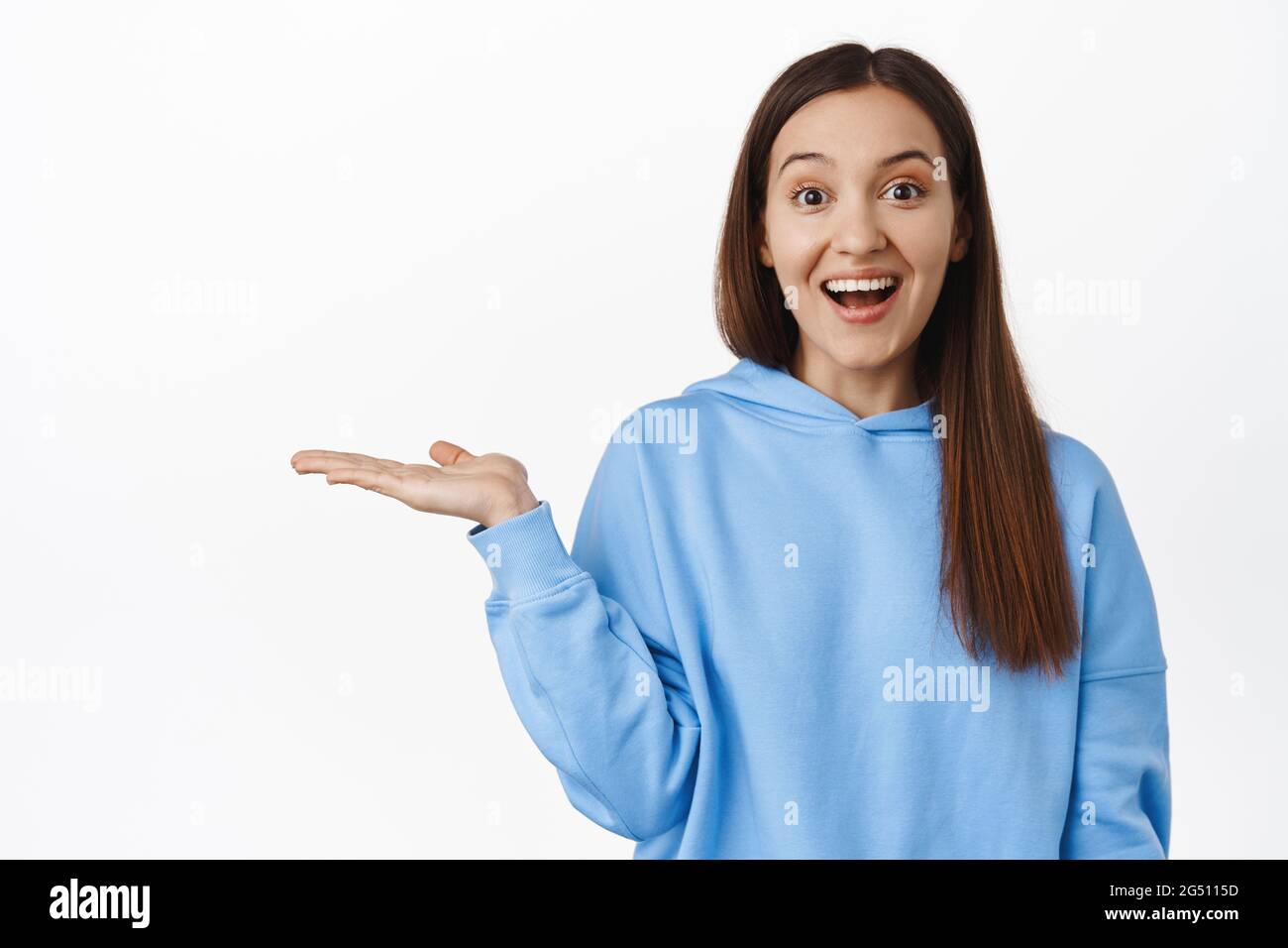 Image of happy cute girl holding in open hand, smiling excited about ...