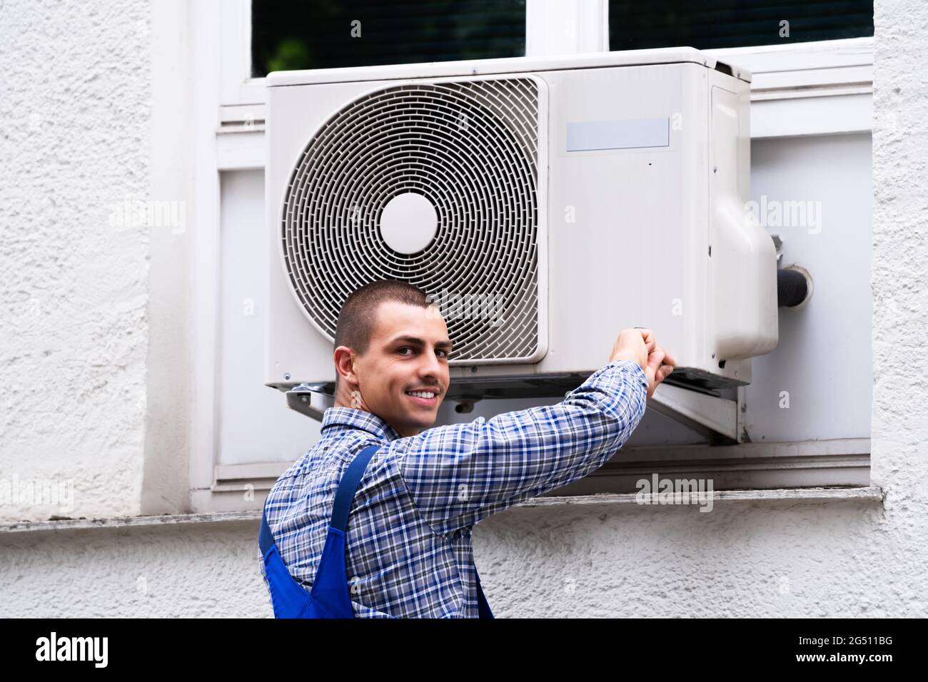 Technician Cleaning And Repairing Air Condition Appliance. AC Unit Maintenance Stock Photo