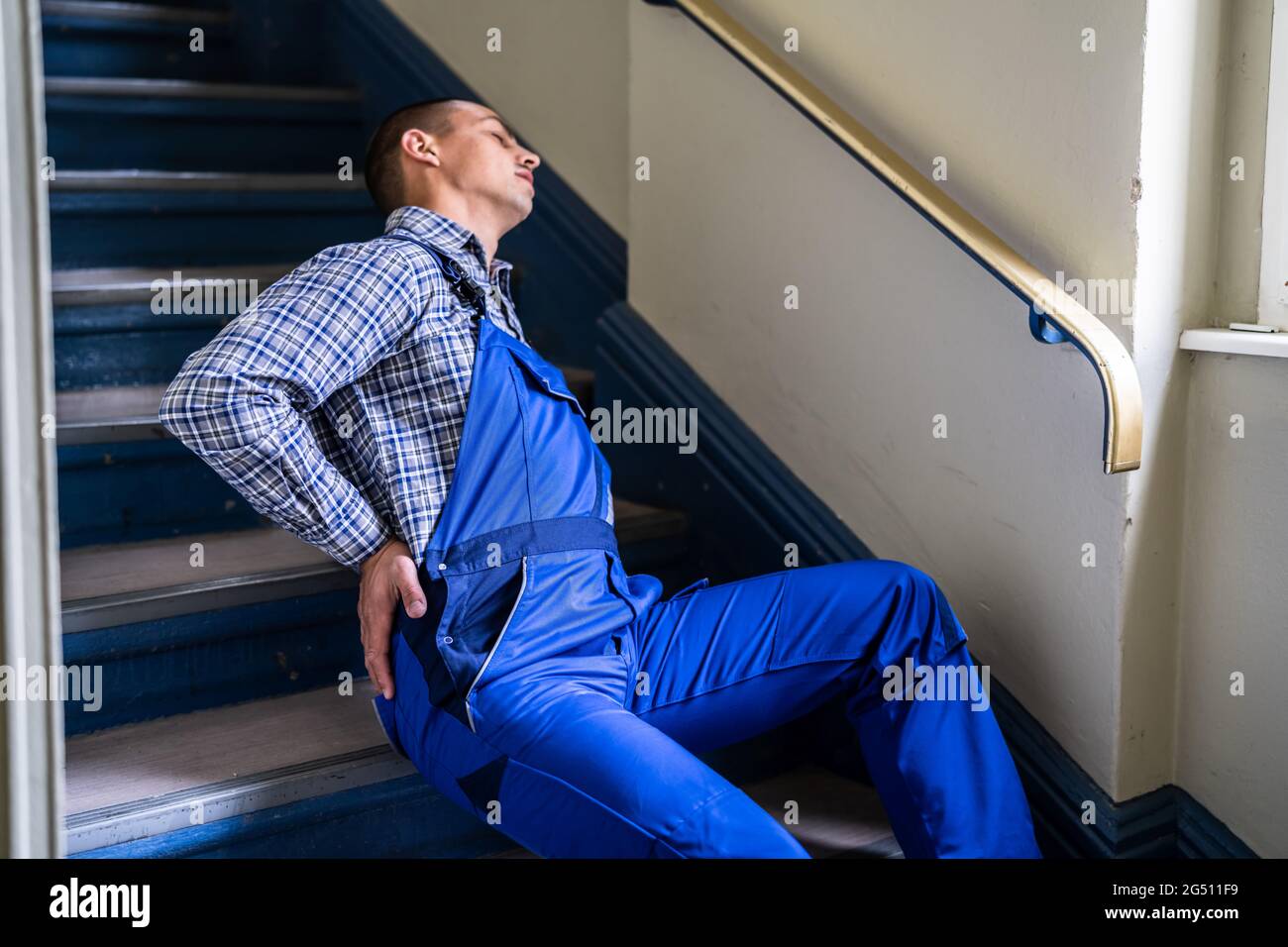 Worker Man Lying On Staircase After Slip And Fall Accident Stock Photo