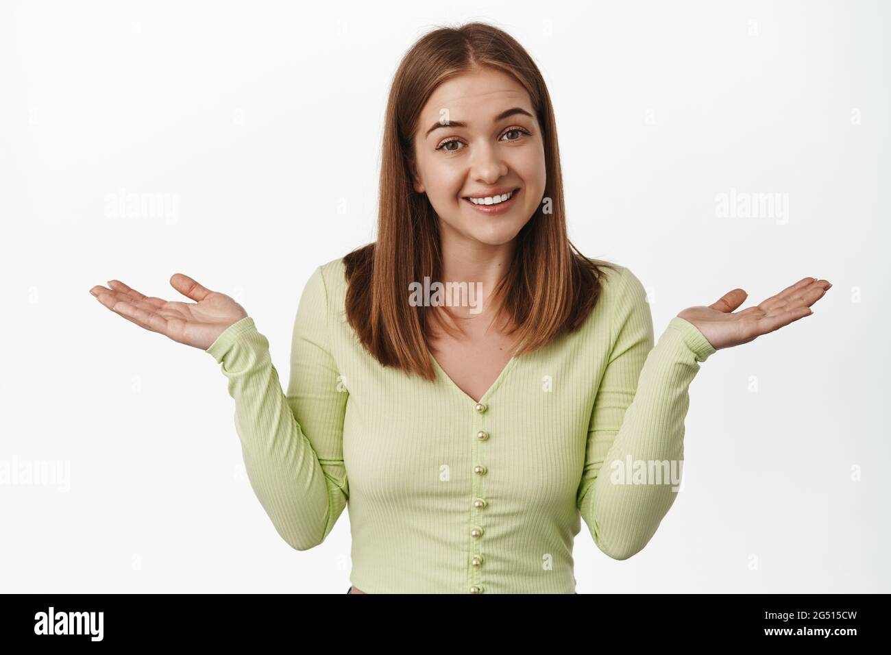 Sorry cant help you. Unbothered smiling girl shrugging shoulders unaware, being clueless, dont know and not care, standing against white background Stock Photo