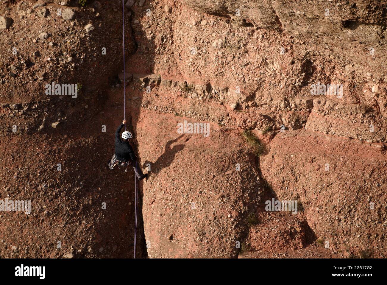 A climber descending the Cavall Bernat rock in Matadepera, in Sant Llorenç del Munt i l'Obac (Barcelona, Catalonia, Spain) Stock Photo