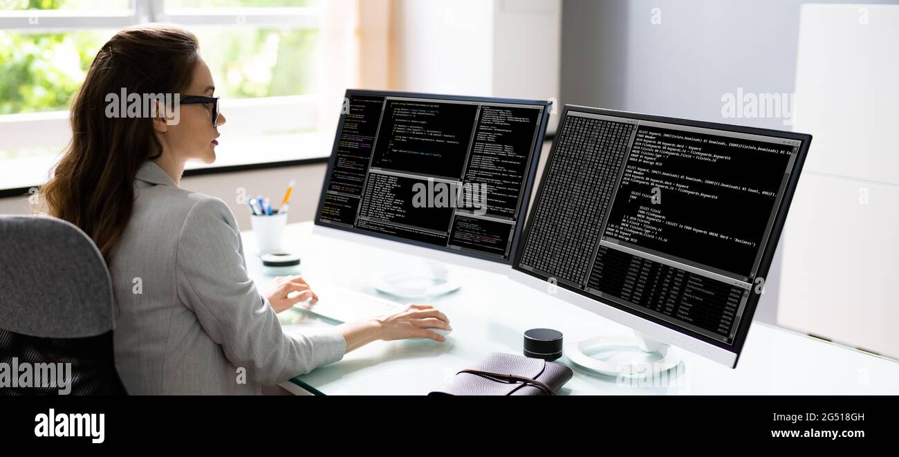 Programmer Woman Coding On Multiple Computer Screens Stock Photo - Alamy