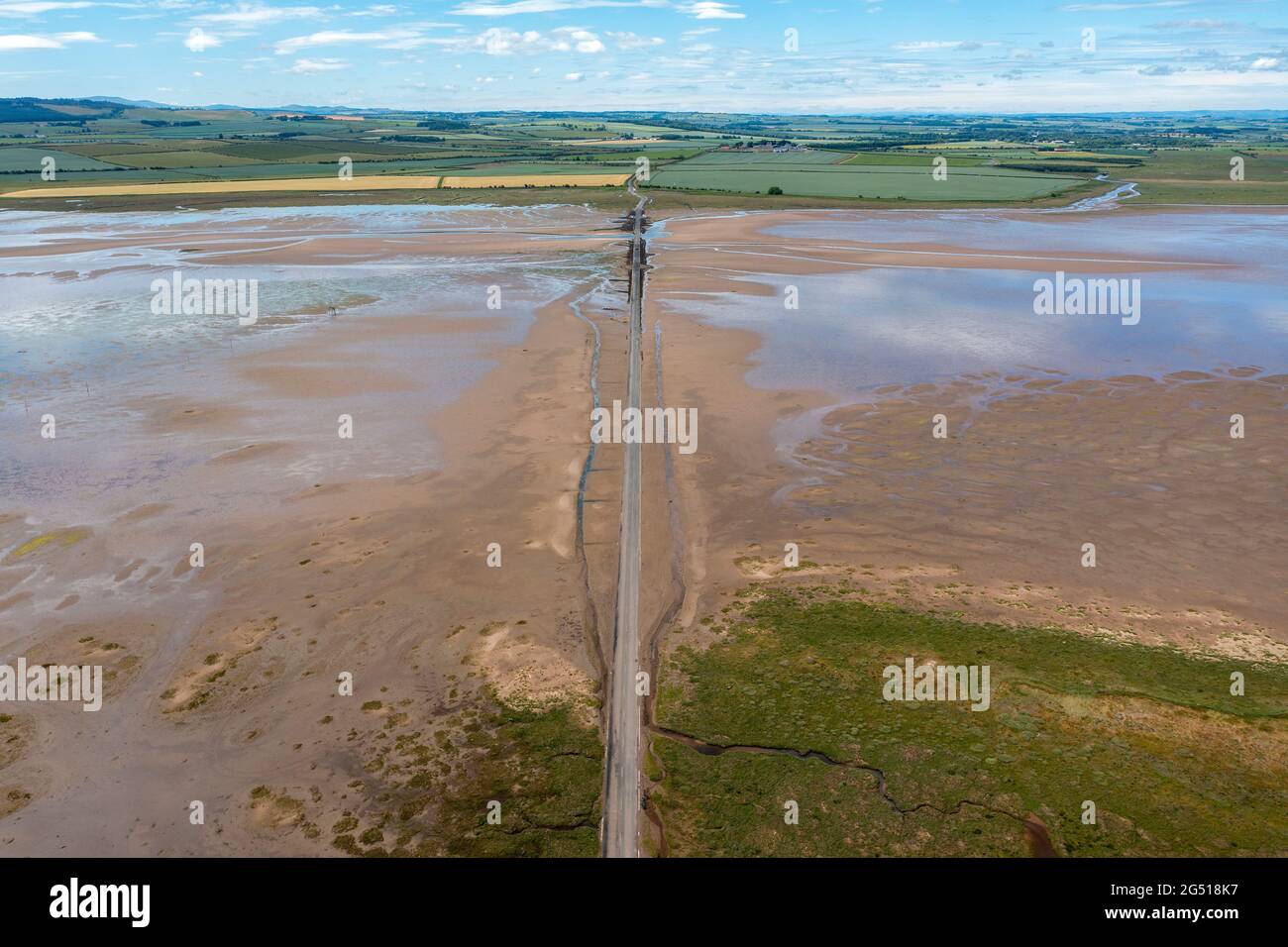Aerial view of the Lindisfarne, (Holy Island) causeway that links it to the Northumberland mainland. The Causeway get covered by the sea at high tide Stock Photo