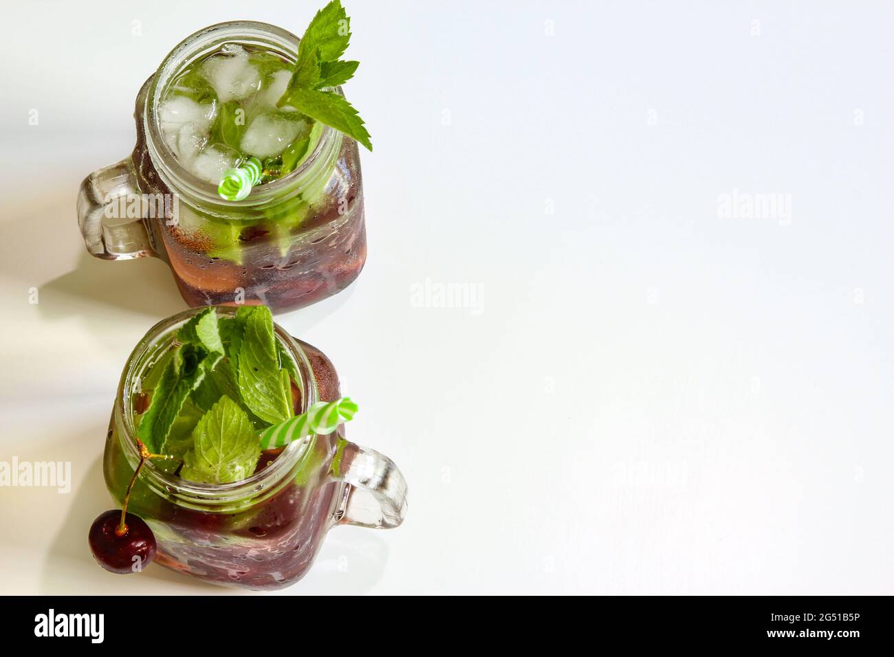 Cold drinks in small bottles. Cherries mint lemonade. Mojito coctail. Stock Photo