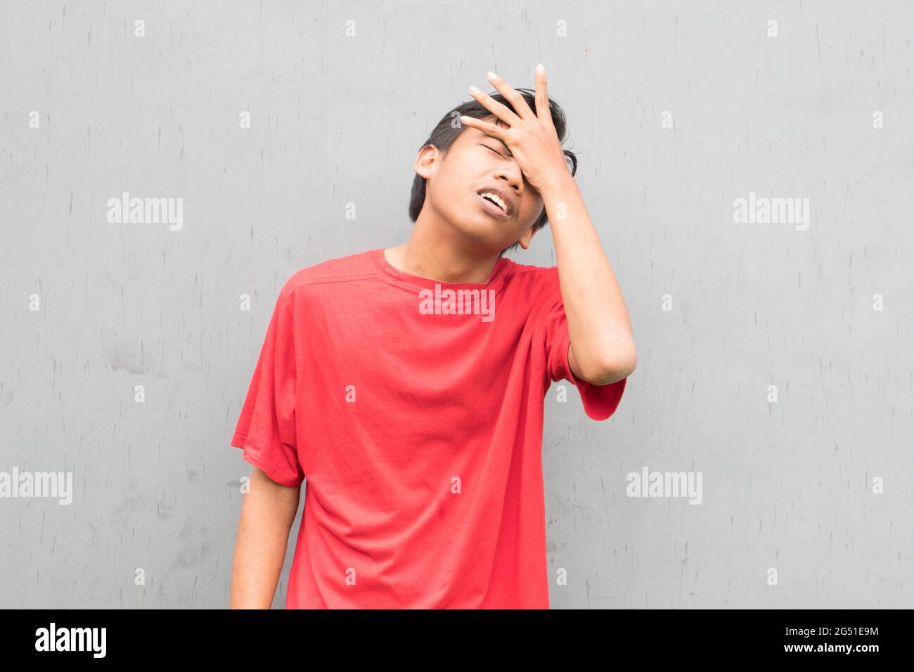 Indonesian guy wearing a red tshirt suffering from a headache Stock