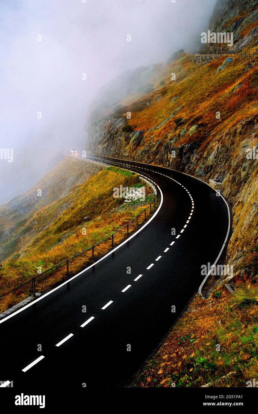 Road on mountainside disappearing into fog, Switzerland Stock Photo