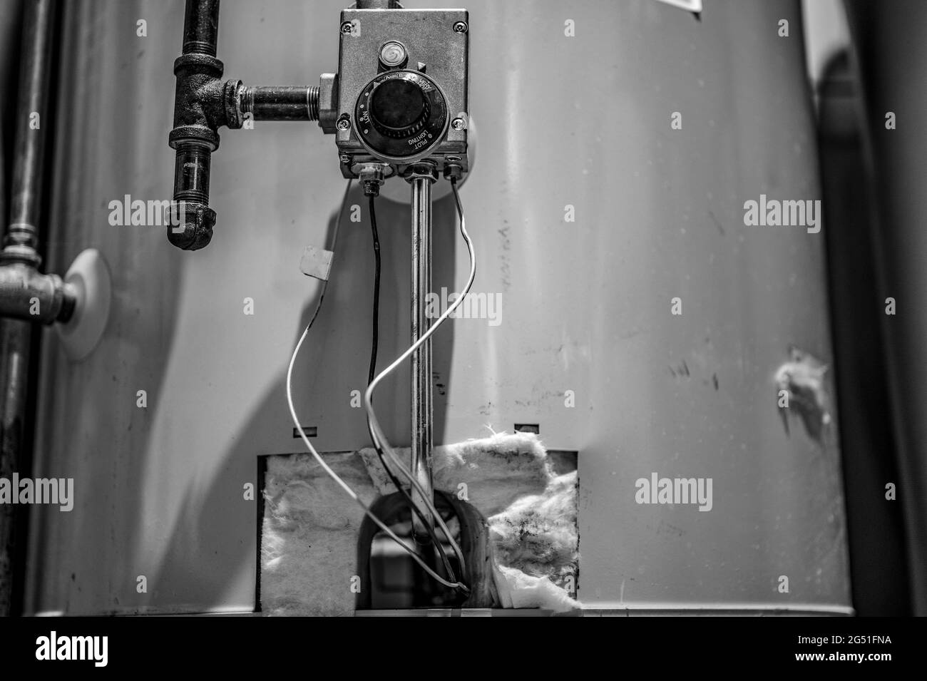Hot water heater pilot light and burner visible with base plate removed Stock Photo