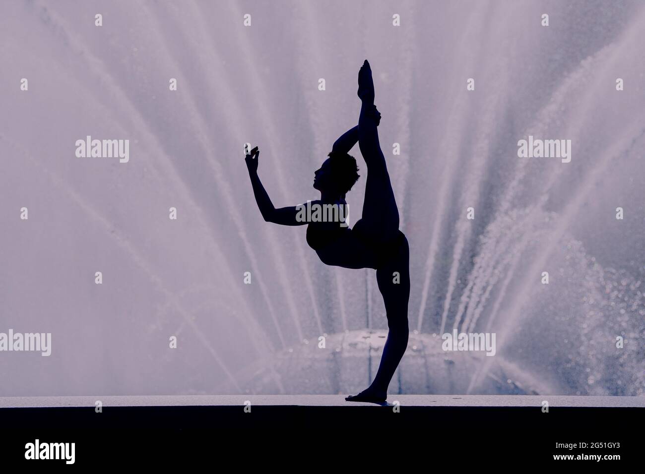 Silhouette of woman doing acrobatic pose against fountain Stock Photo
