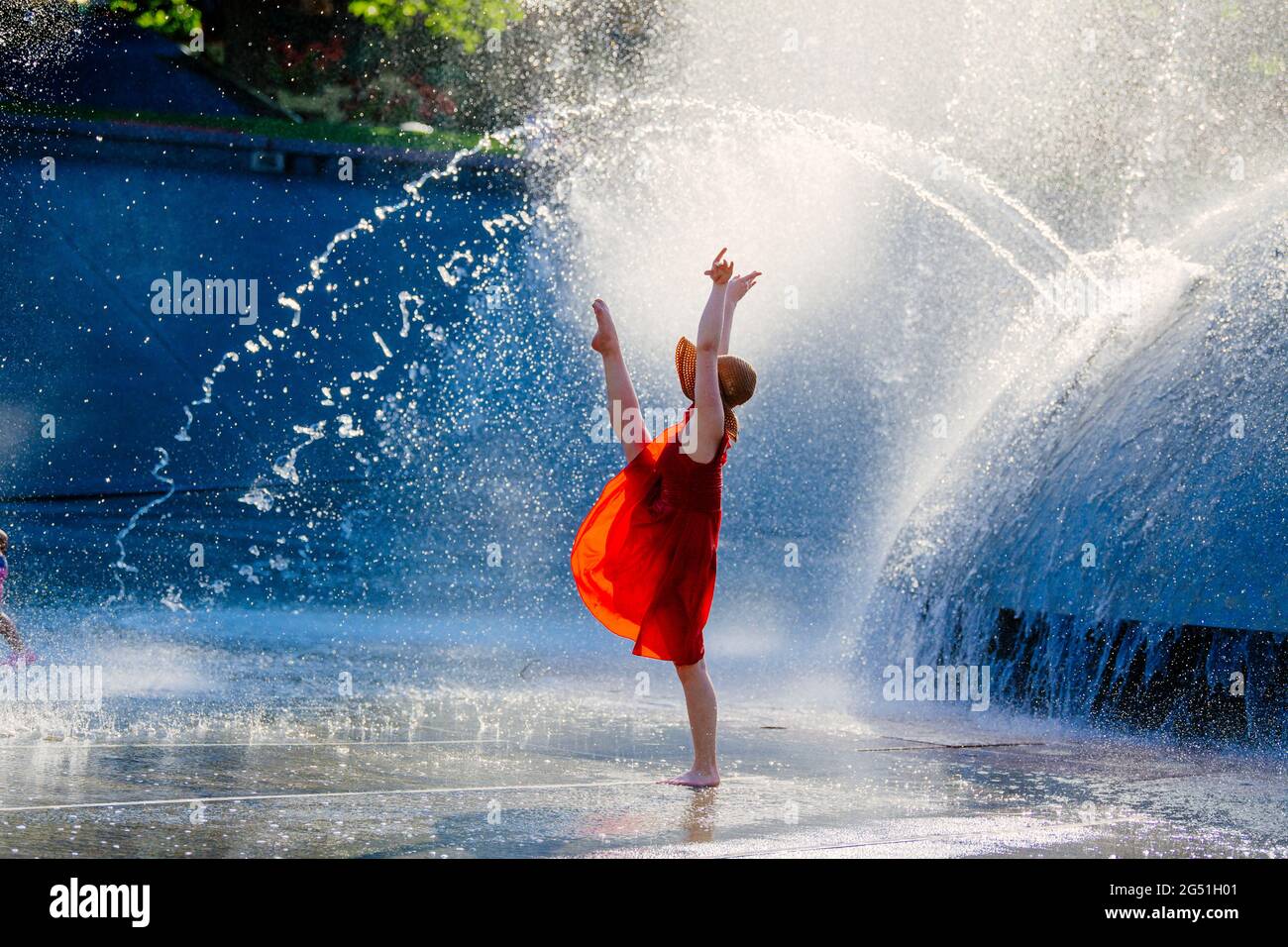 Woman in red dress dancing against fountain Stock Photo