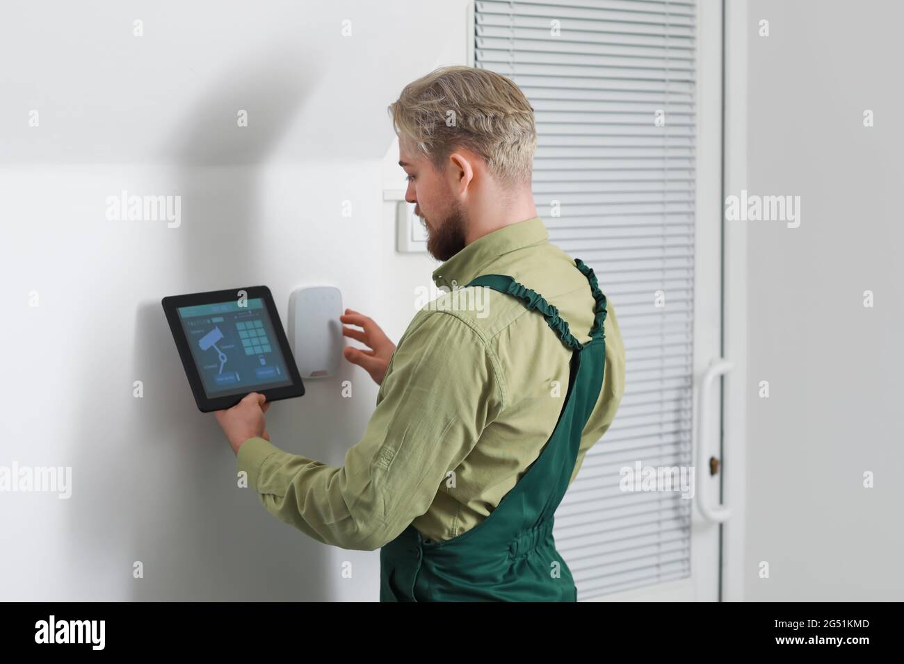 Worker with tablet computer checking alarm system indoors Stock Photo