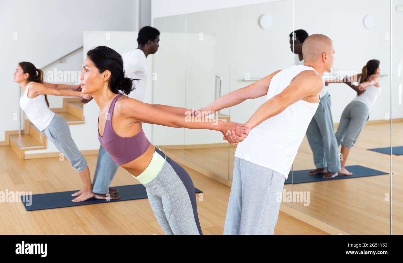 Couples practicing yoga with partner at studio Stock Photo