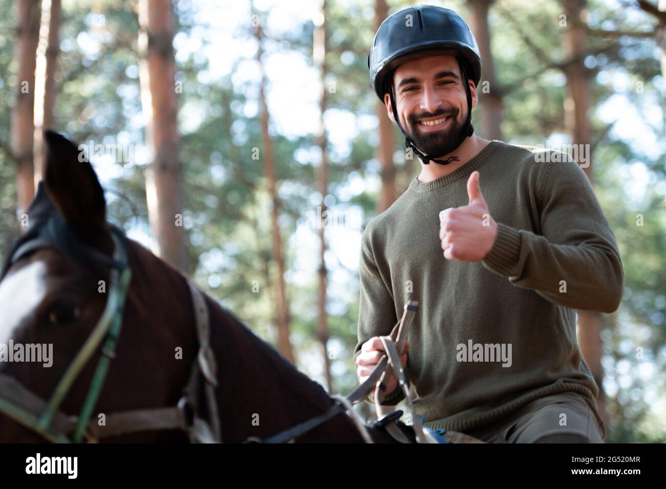 portrait-of-confident-male-jockey-with-horse-standing-on-field-and
