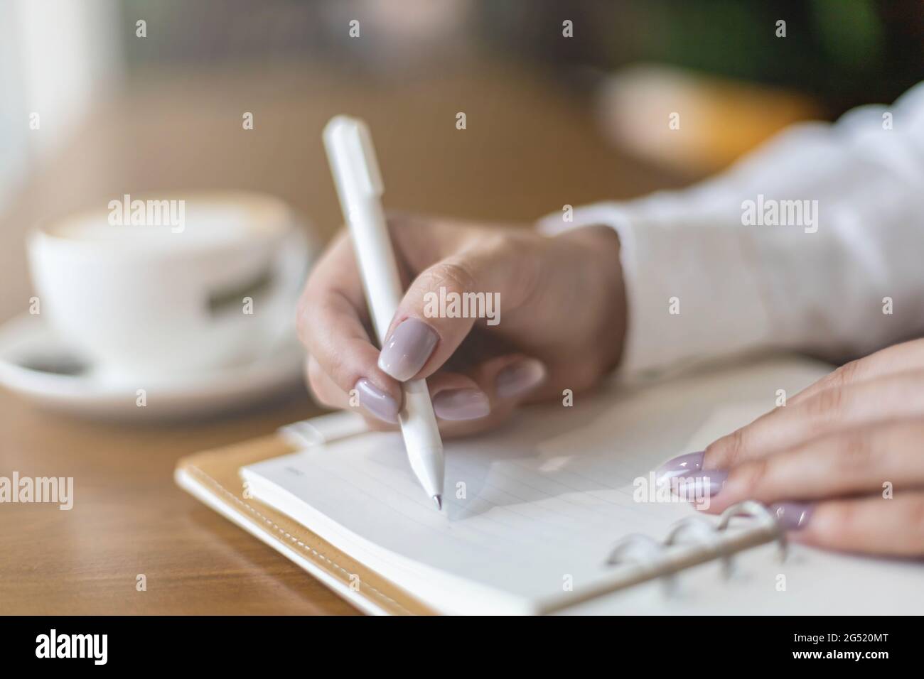 Closeup female hands making paper notes in notepad use pen table cafeteria writing diary, planning Stock Photo