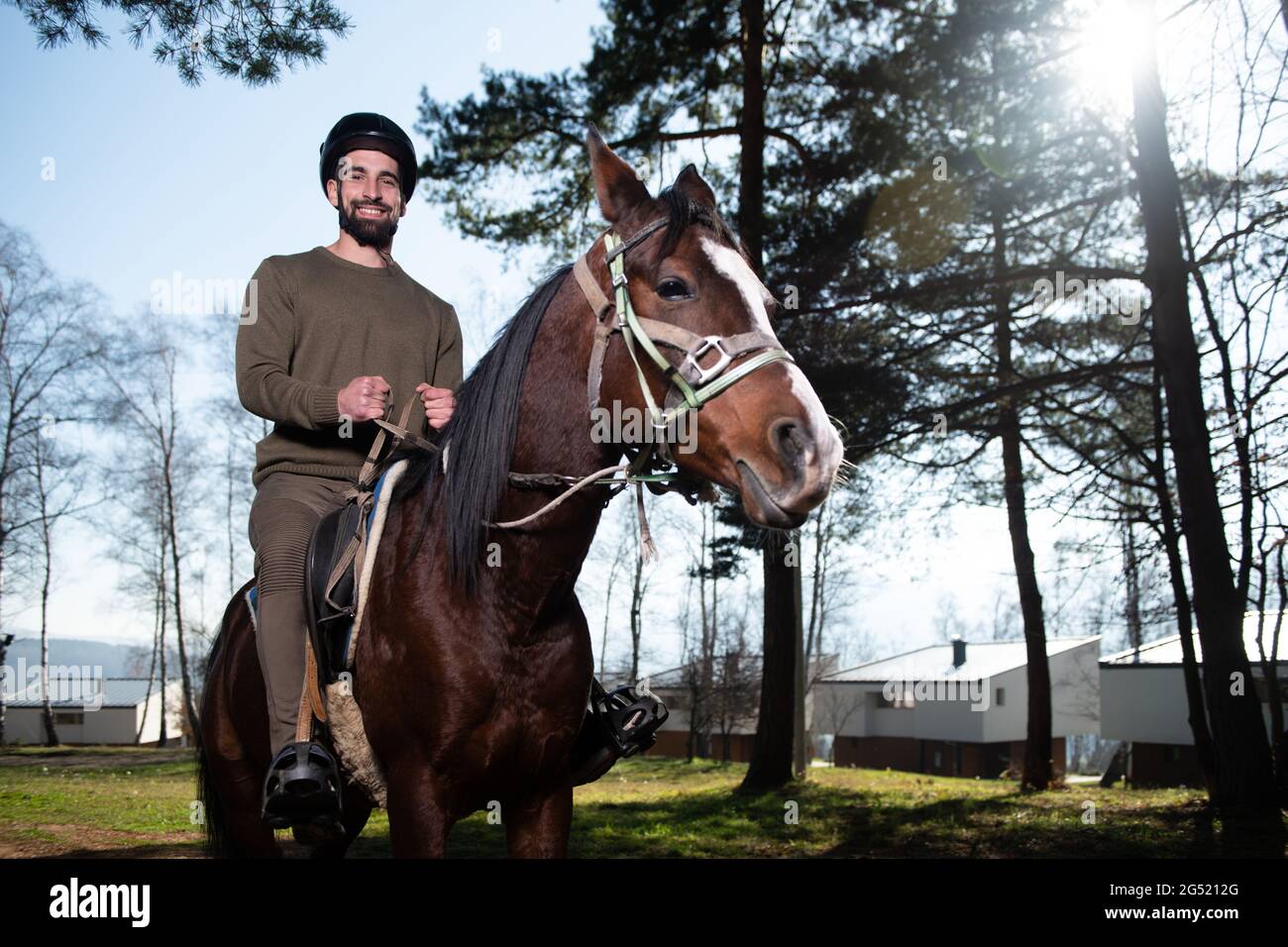 Portrait of Confident Male Jockey With Horse Standing on Field Stock Photo