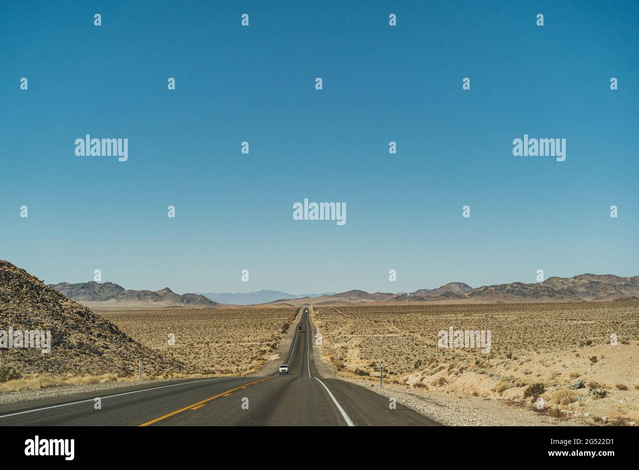 Desert highway road leading to the horizon against clear blue sky and ...