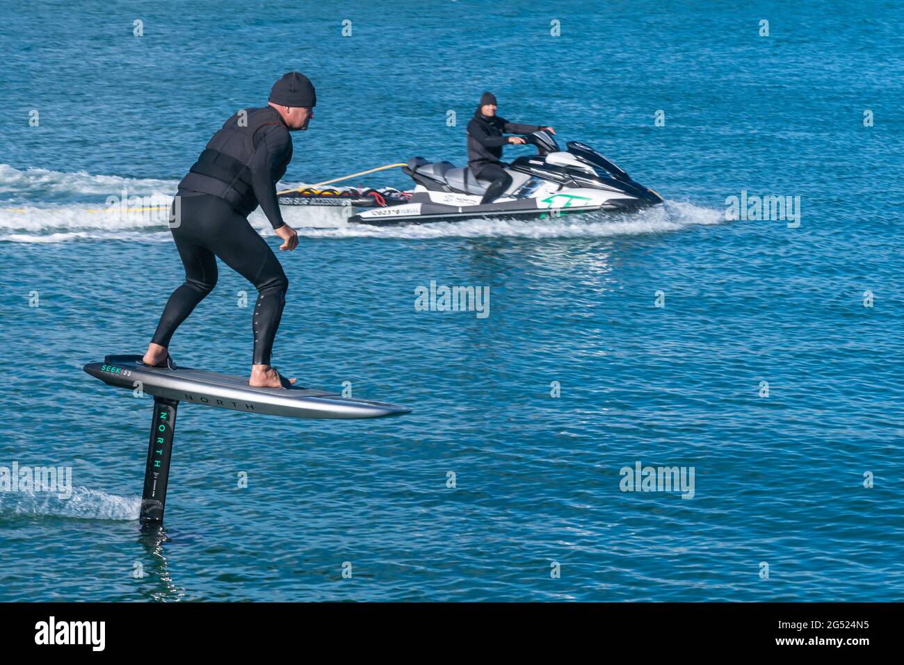Auckland New Zealand - June 17 2021;Foil board being towed behind jet-ski on Auckland harbor Stanley Bay Stock Photo