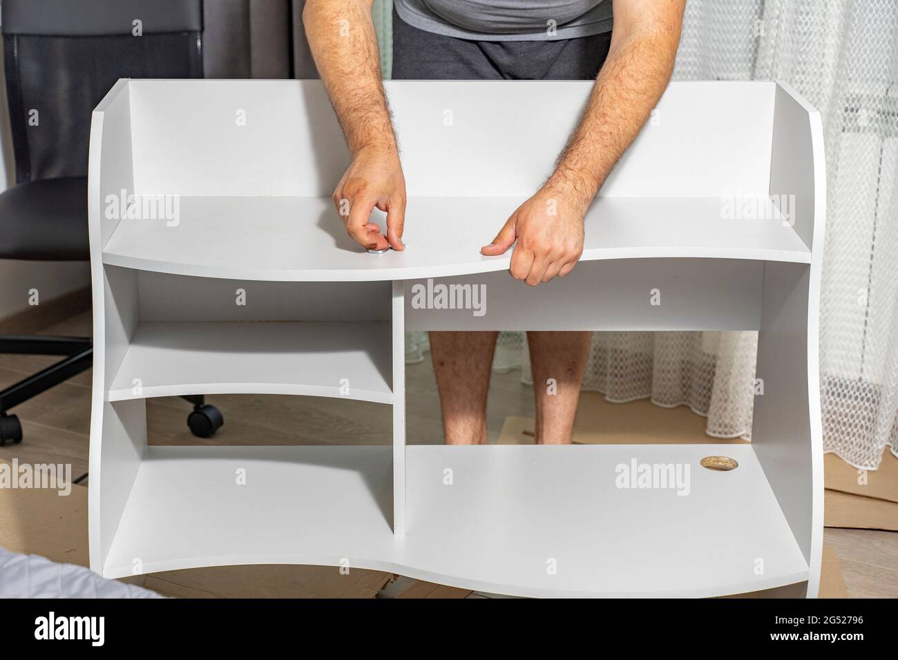 master assembles a new shelf at home Stock Photo