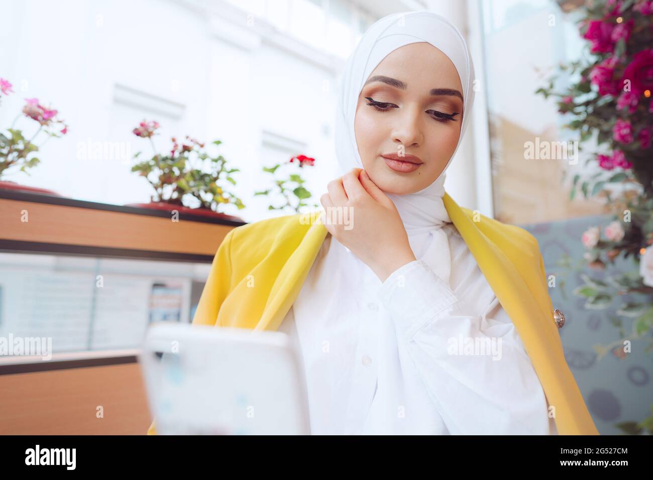 Young muslim woman in hijab using her smartphone in cafe Stock Photo ...
