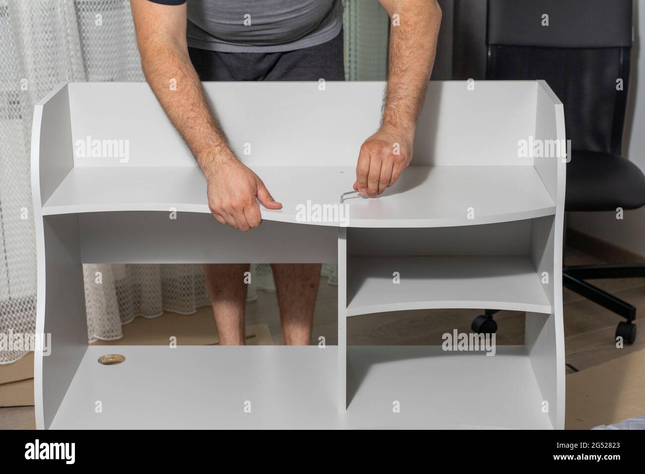 a man assembles a new shelf at home. Stock Photo