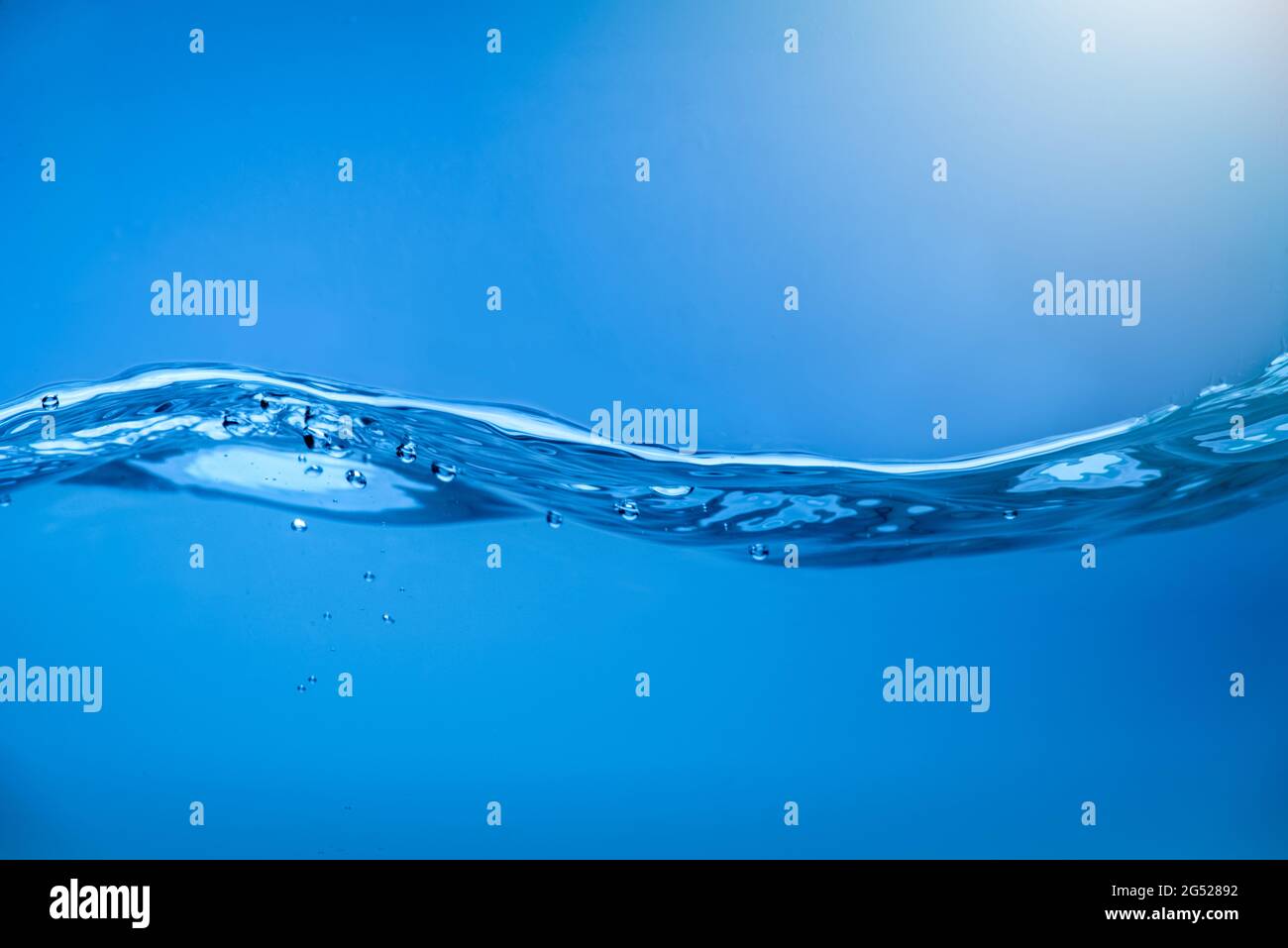Water waves with air bubbles in clear blue water. Stock Photo