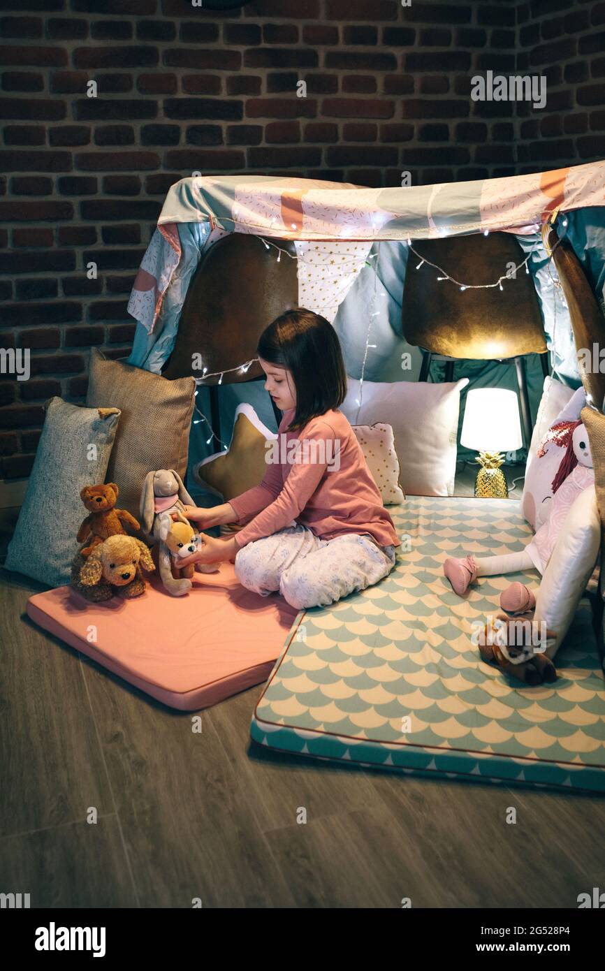 Girl playing with stuffed animals in a teepee Stock Photo