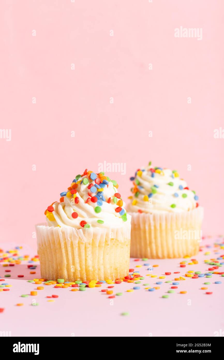 White cream cupcake with color sprinkles on rose Stock Photo
