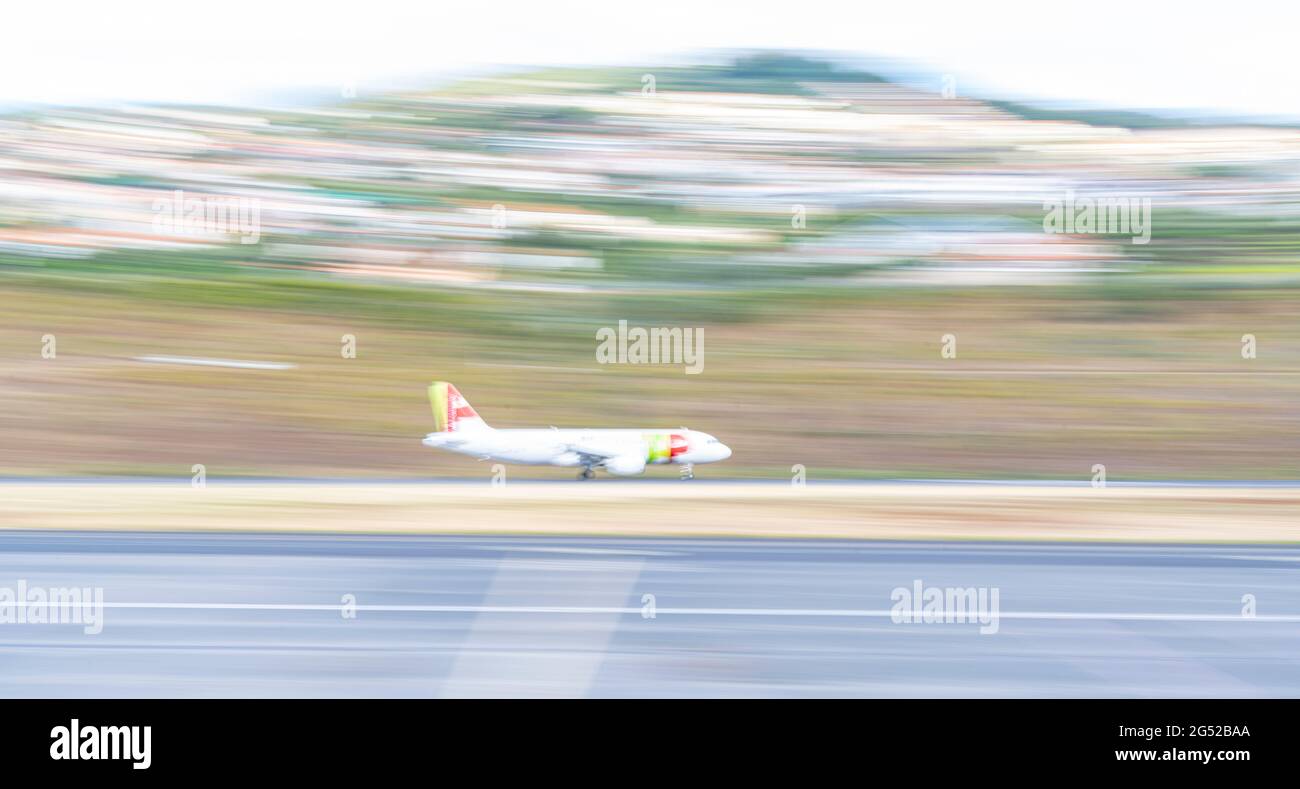 Passenger aircraft landing on runway at Cristiano Ronaldo international airport, panning shot, Funchal, Madeira island, Portugal Stock Photo