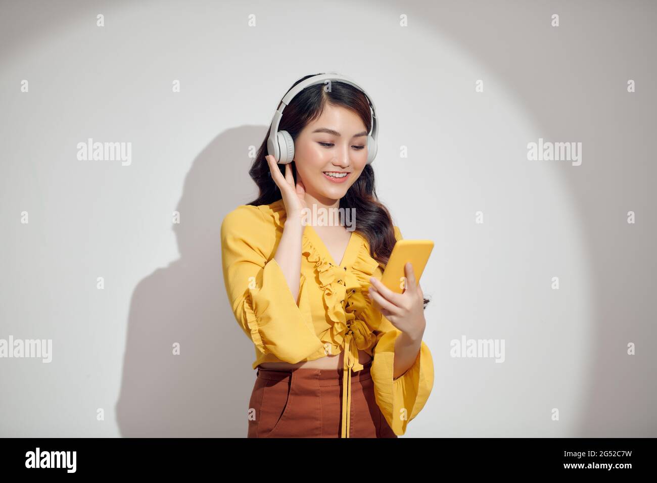 Smiling woman listening music in headphones and using smartphone over ...
