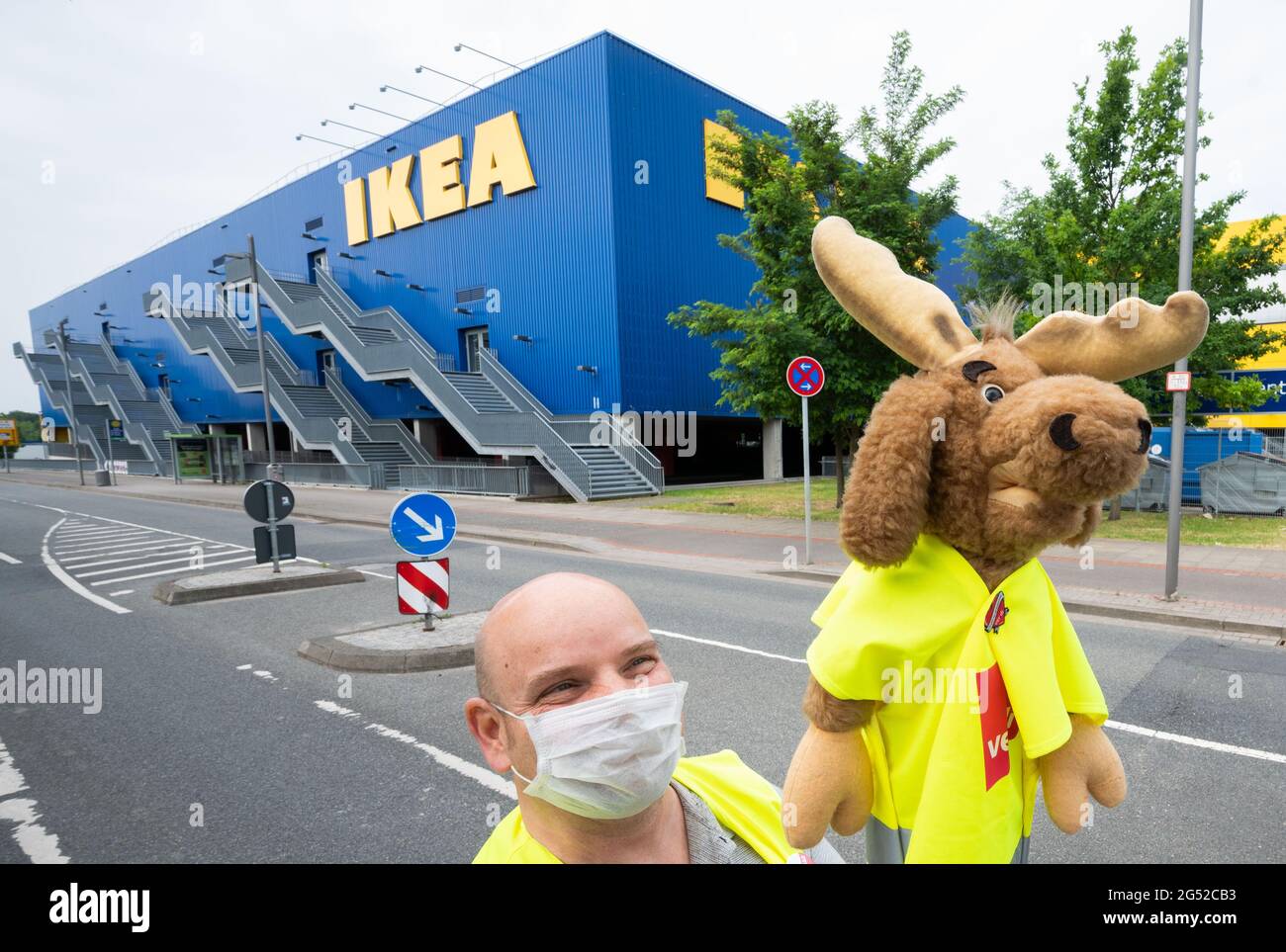 Hanover, Germany. 25th June, 2021. An employee of the furniture store chain  Ikea stands with a cloth cup during a strike in front of the Ikea Expo  Park. The trade union Verdi