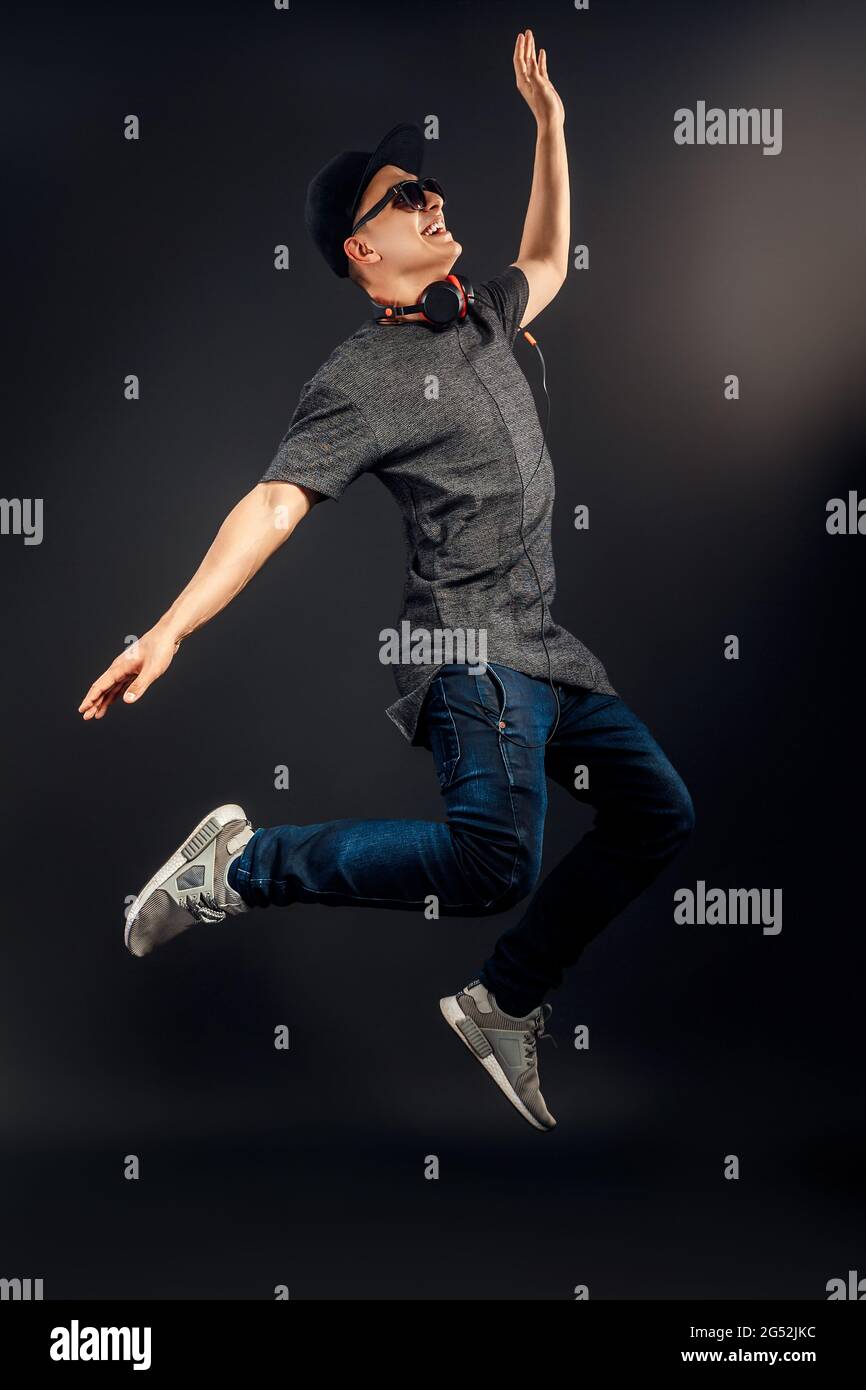 Full length image of man which listening to music and jumping in studio. Vertical image Stock Photo