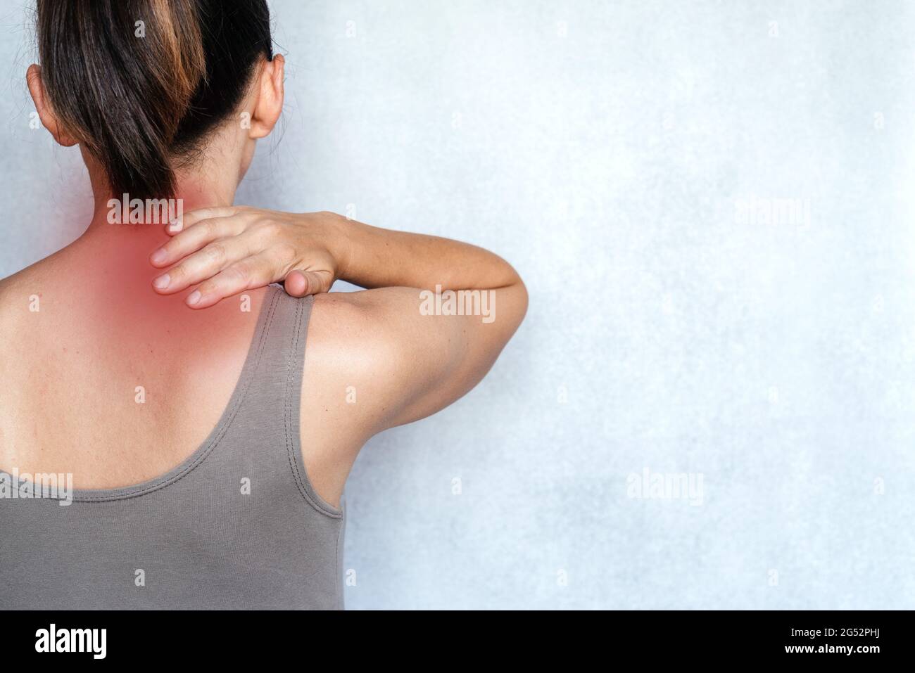 A woman suffering from neck pain and massaging her neck to releive pain ...