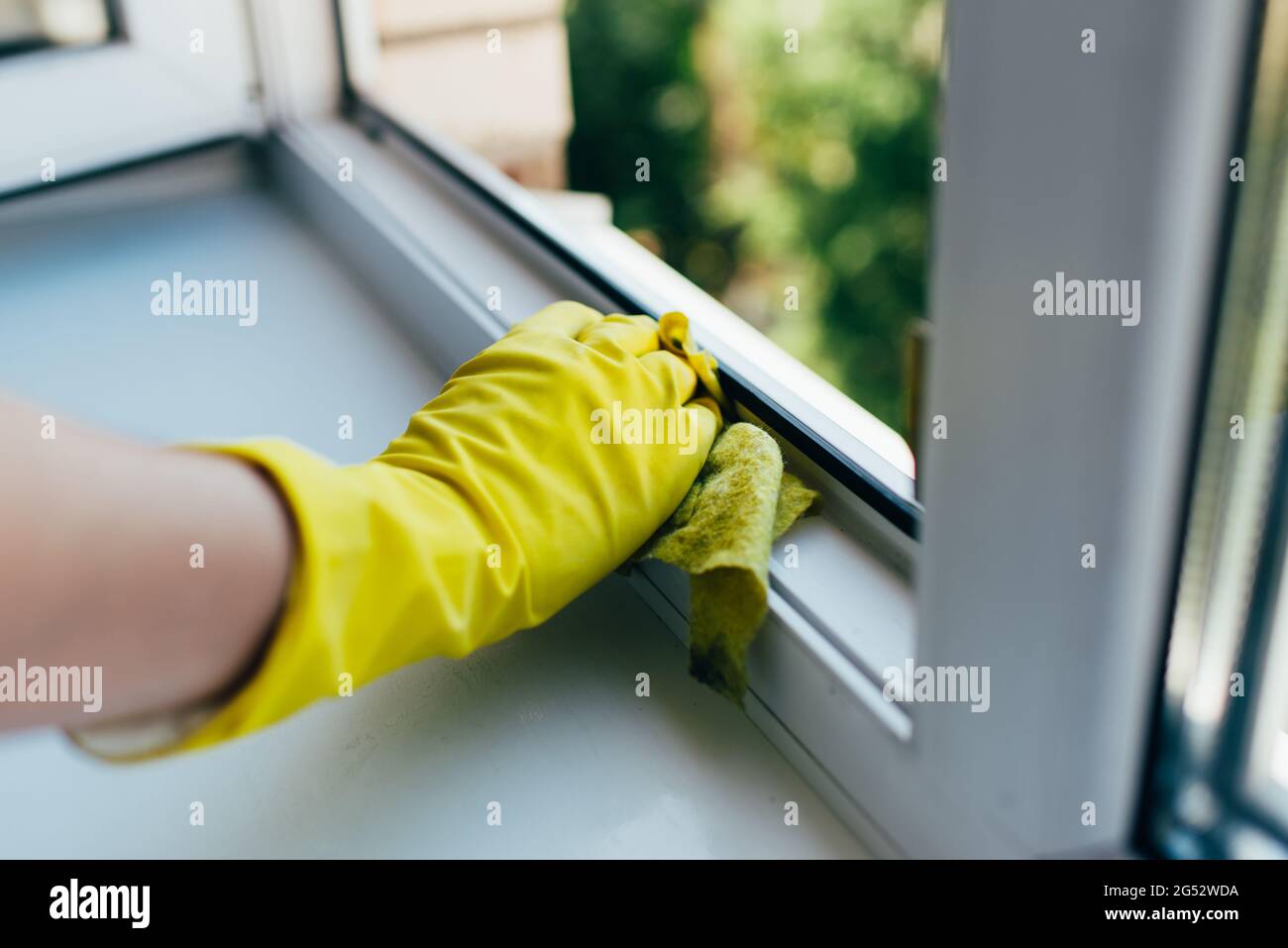 A person wearing gloves washes the window frame with a cleaning cloth ...